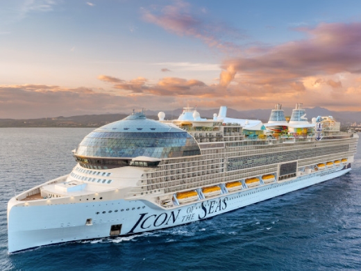 Icon of the Seas cruise ship sailing at sunset with golden clouds overhead