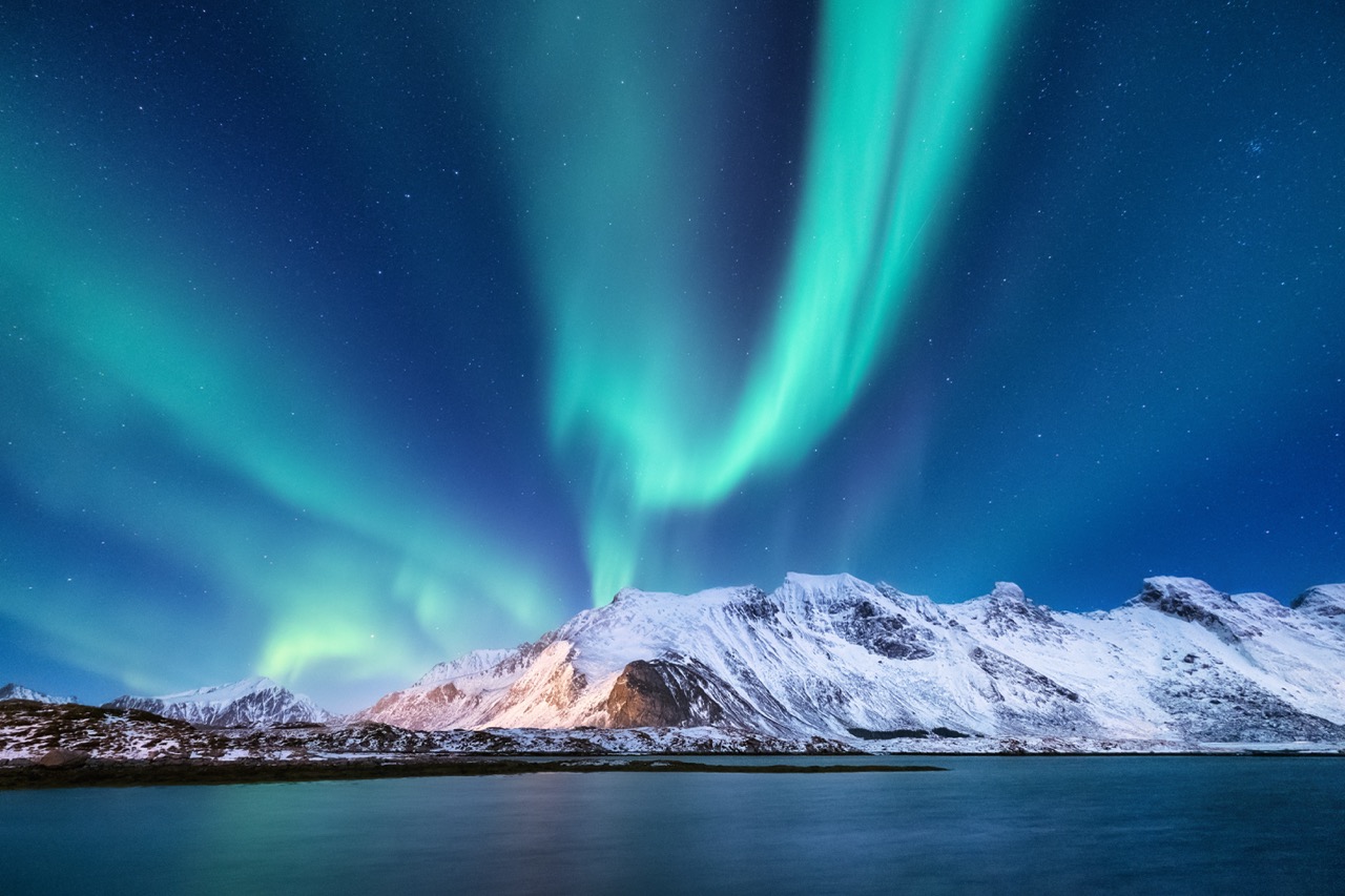 Northen light under mountains. Beautiful natural landscape in the Norway Spectacular aurora borealis dancing in vibrant green and blue hues above snow-covered mountains and a calm fjord waters.