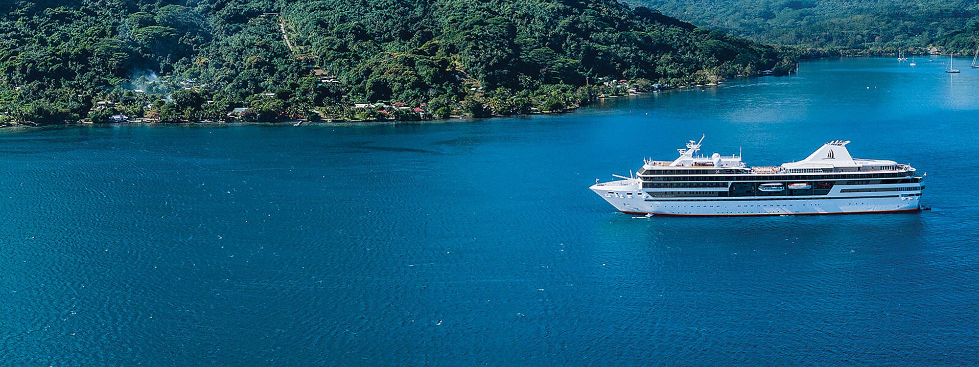 Paul Gauguin cruise ship anchored in turquoise Polynesian lagoon