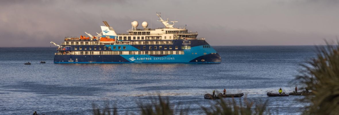 Polar Latitudes expedition ship anchored in calm coastal waters with small Zodiac boats nearby