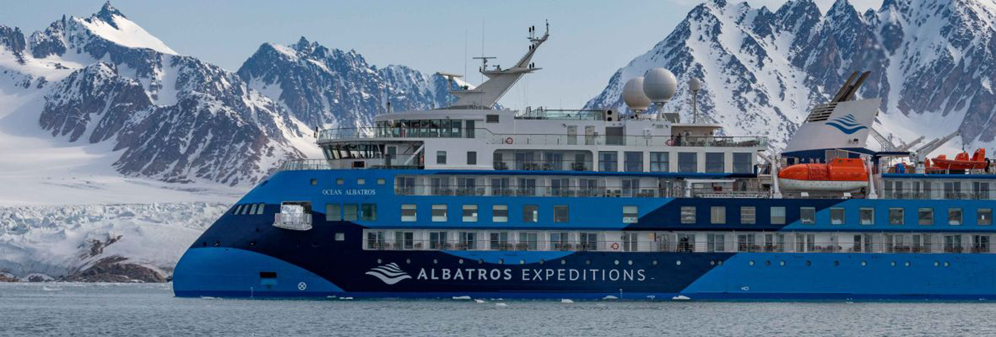 Polar Latitudes expedition ship navigating through icy waters with snow-capped mountains in the background
