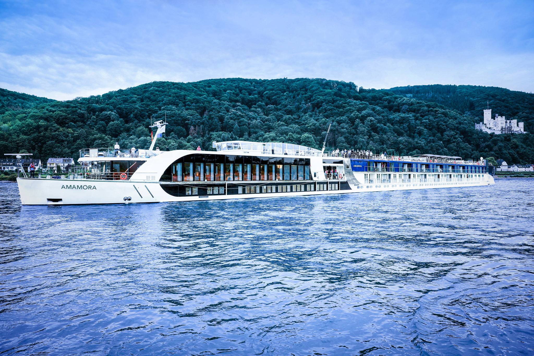 AmaMora River Cruise Ship on Scenic Waterway AmaMora river cruise ship sailing on the Rhine with castle and forested hills