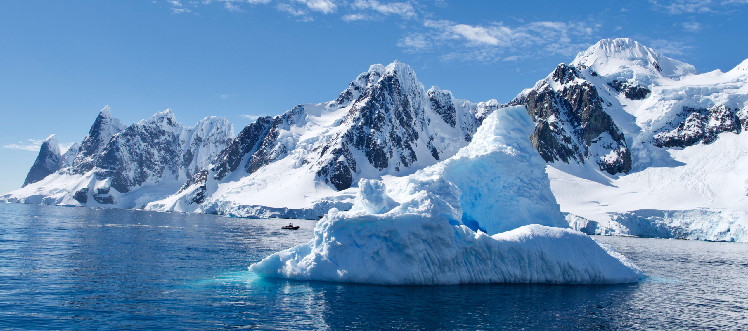 Antarctic Iceberg and Snowy Mountain Landscape A massive blue-white iceberg floating in the foreground with dramatic snow-covered mountains