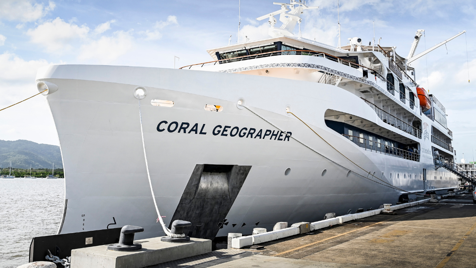 Coral Geographer Cruise Ship at Port Coral Geographer cruise ship docked at port with mountains in the background