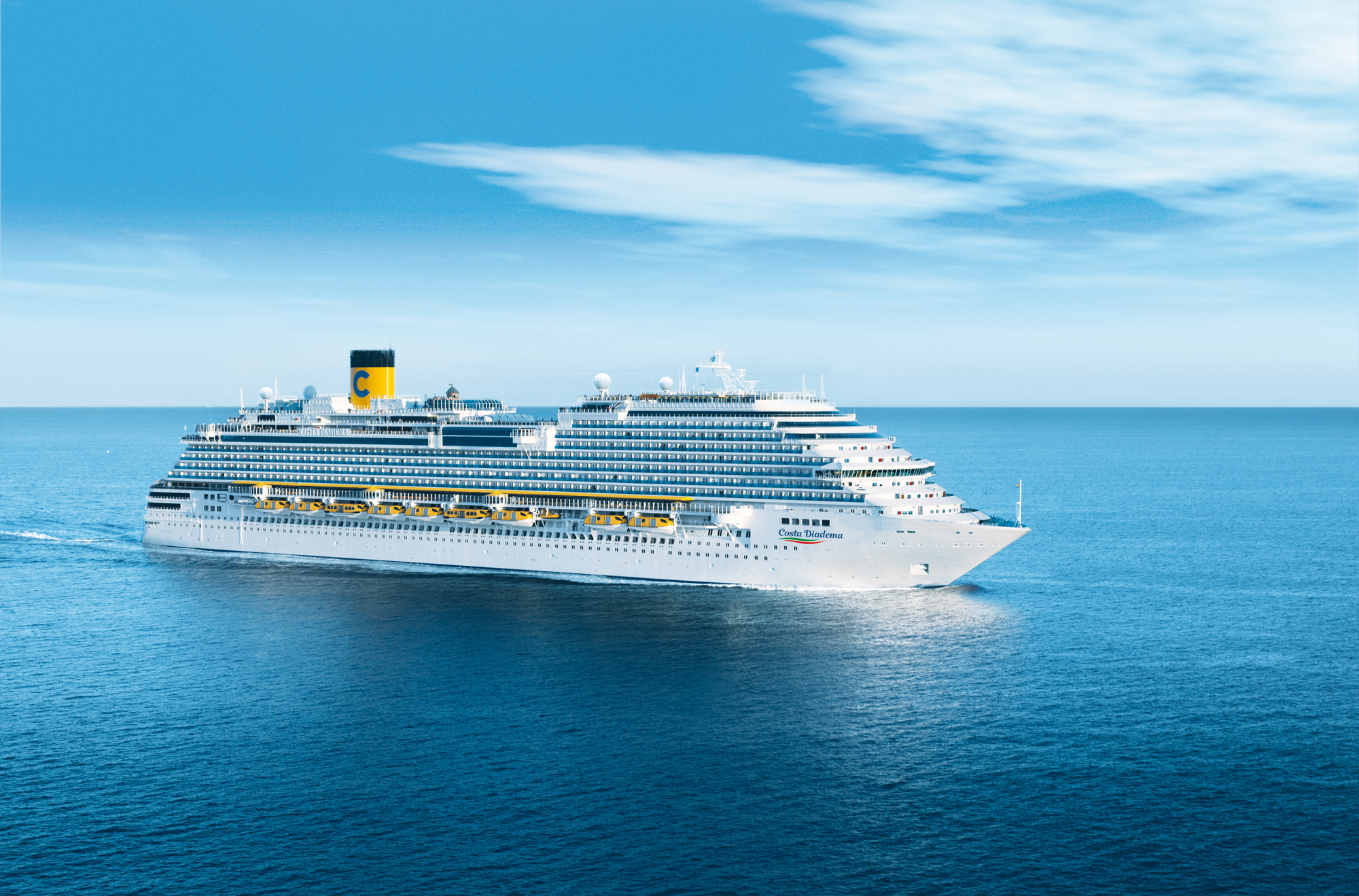 A large white cruise ship from the Costa cruise line sailing on a calm blue ocean under a clear sky