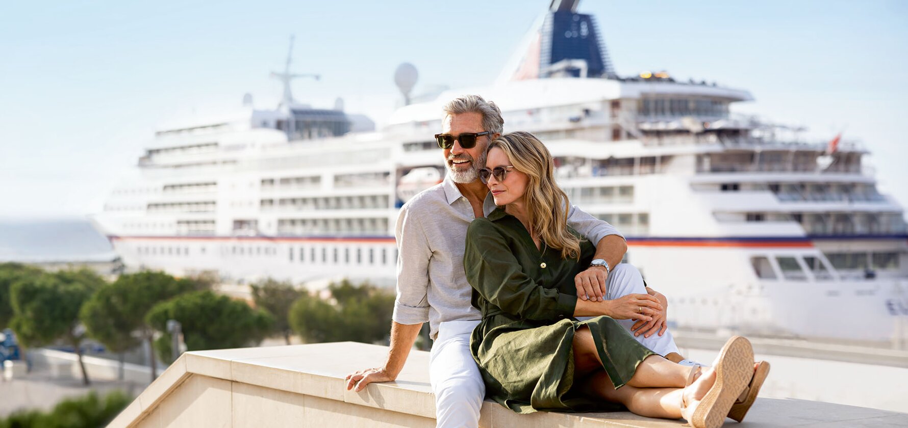 A couple enjoying a cruise ship view from a waterfront promenade