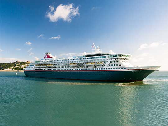Cruise Ship Anchored in Tropical Waters A large modern cruise ship is anchored in crystal-clear turquoise waters near a tropical beach