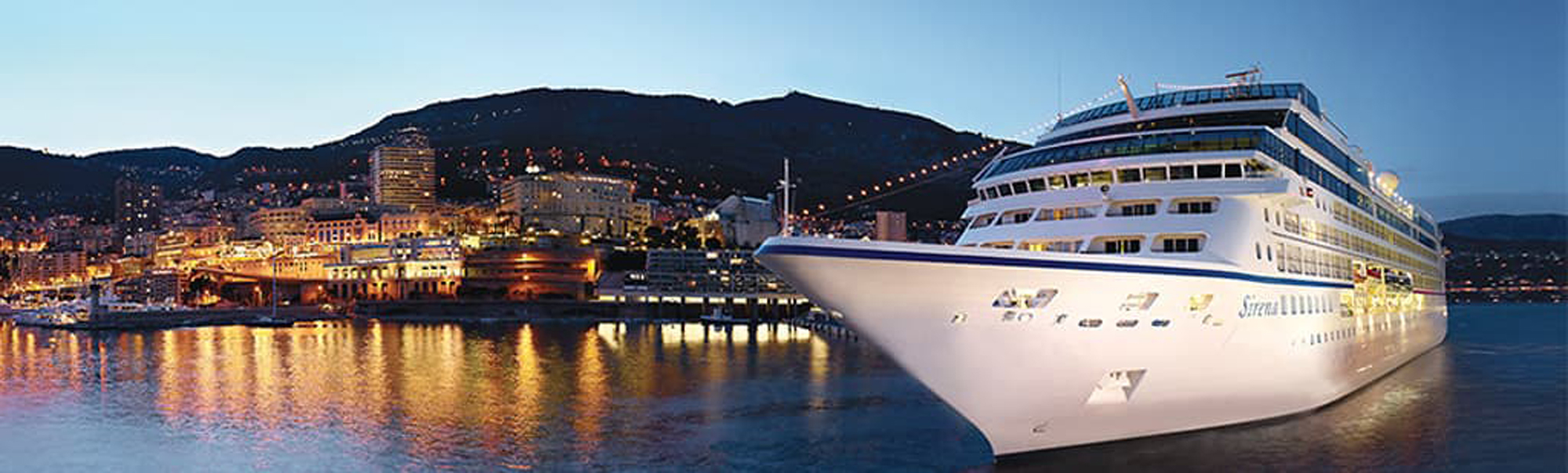 Cruise Ship Docked in Coastal City at Night A large white cruise ship moored at a vibrant nighttime port with illuminated city buildings
