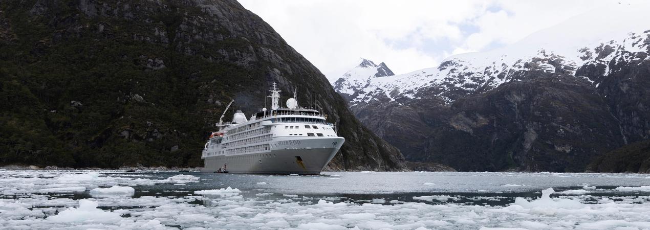 Cruise Ship Navigating Icy Alaskan Fjords A white cruise ship sailing through ice-filled waters surrounded by dramatic snow-capped mountains