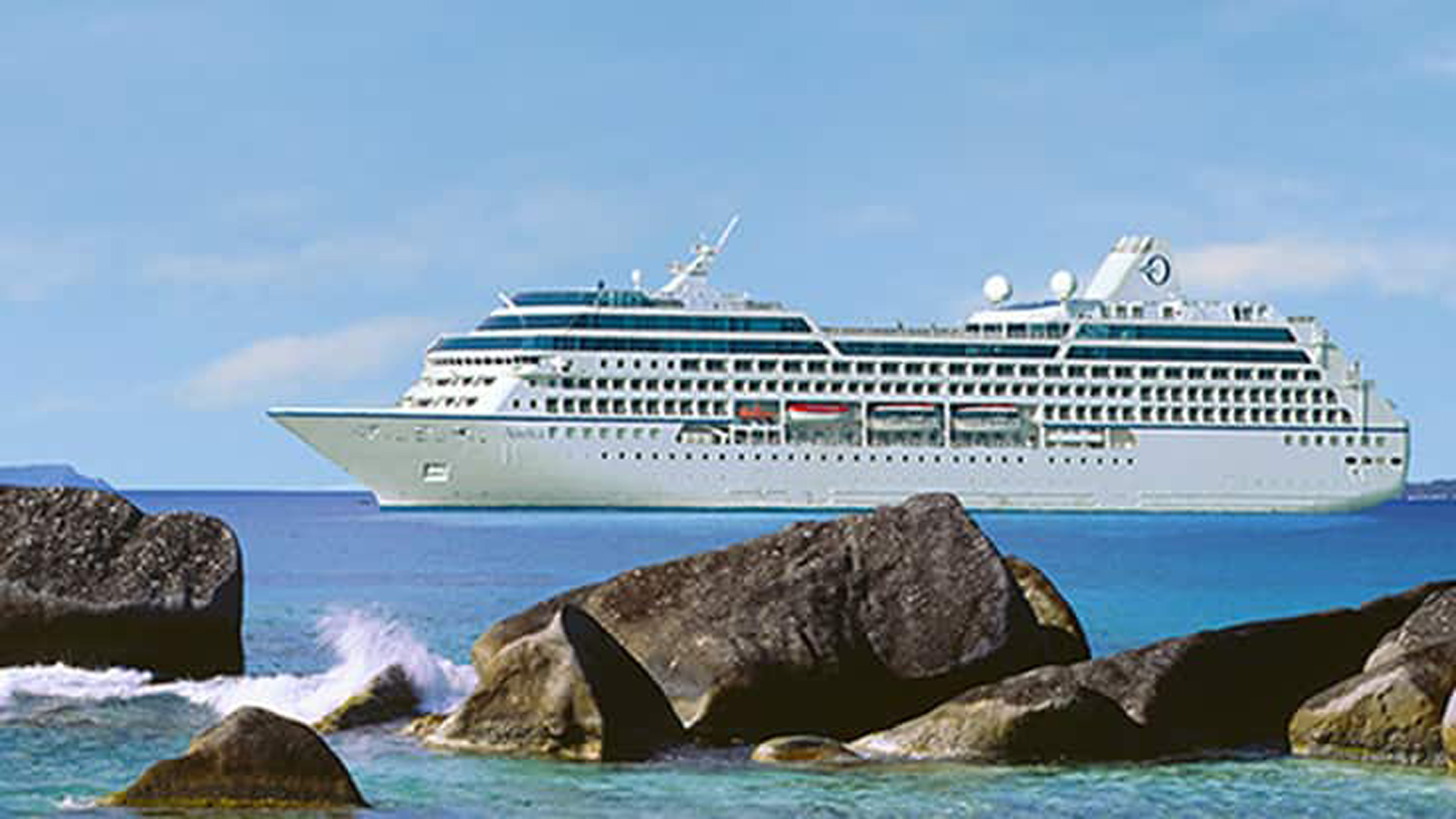 Cruise Ship Sailing Past Rocky Coastline A white and blue cruise ship sailing on turquoise waters near large rocky formations in