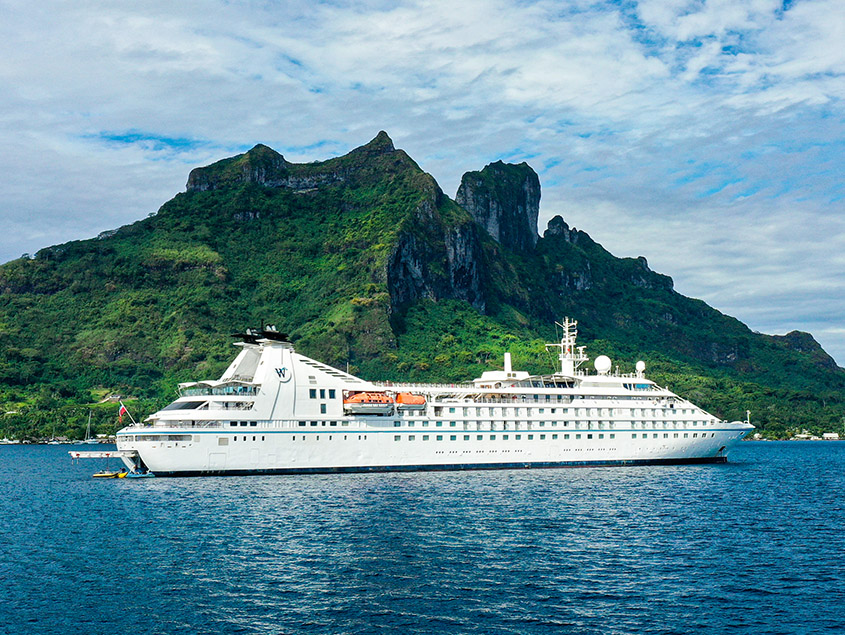Cruise Ship at Tropical Island Destination A pristine white cruise ship anchored in turquoise waters near a lush green mountainous island
