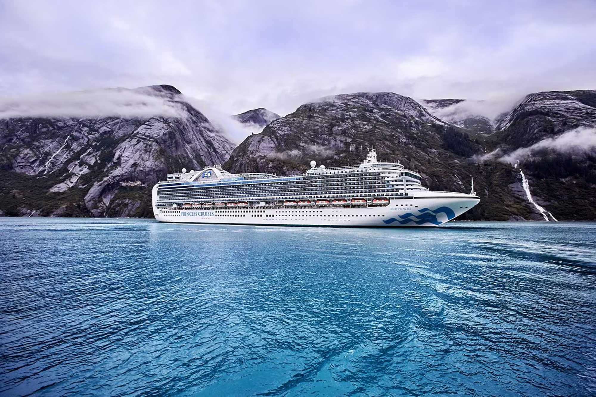 Cruise Ship in Misty Alaskan Fjords A large white Princess Cruises ship sailing through a dramatic fjord landscape with steep rocky