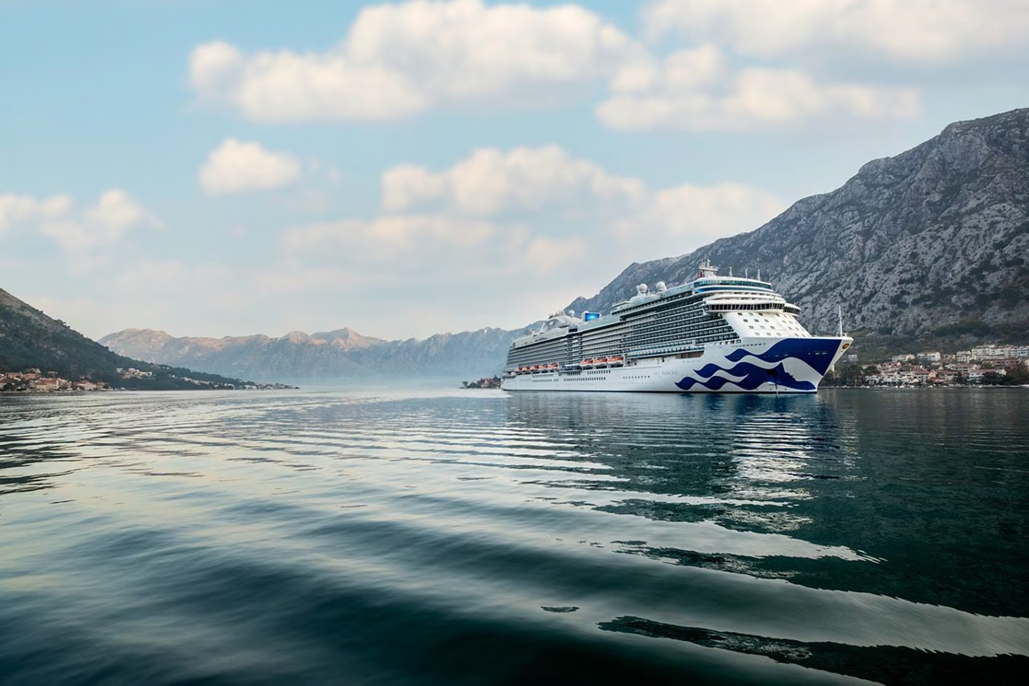 Cruise Ship in Scenic Mountain Fjord A large modern cruise ship sailing through a picturesque mountain landscape with rocky peaks