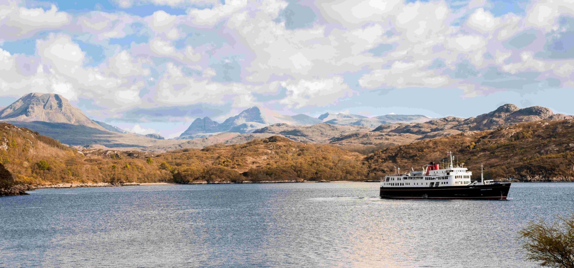 Cruise Ship in Scottish Highlands Waters A classic expedition cruise ship anchors in calm blue waters with dramatic Scottish Highland