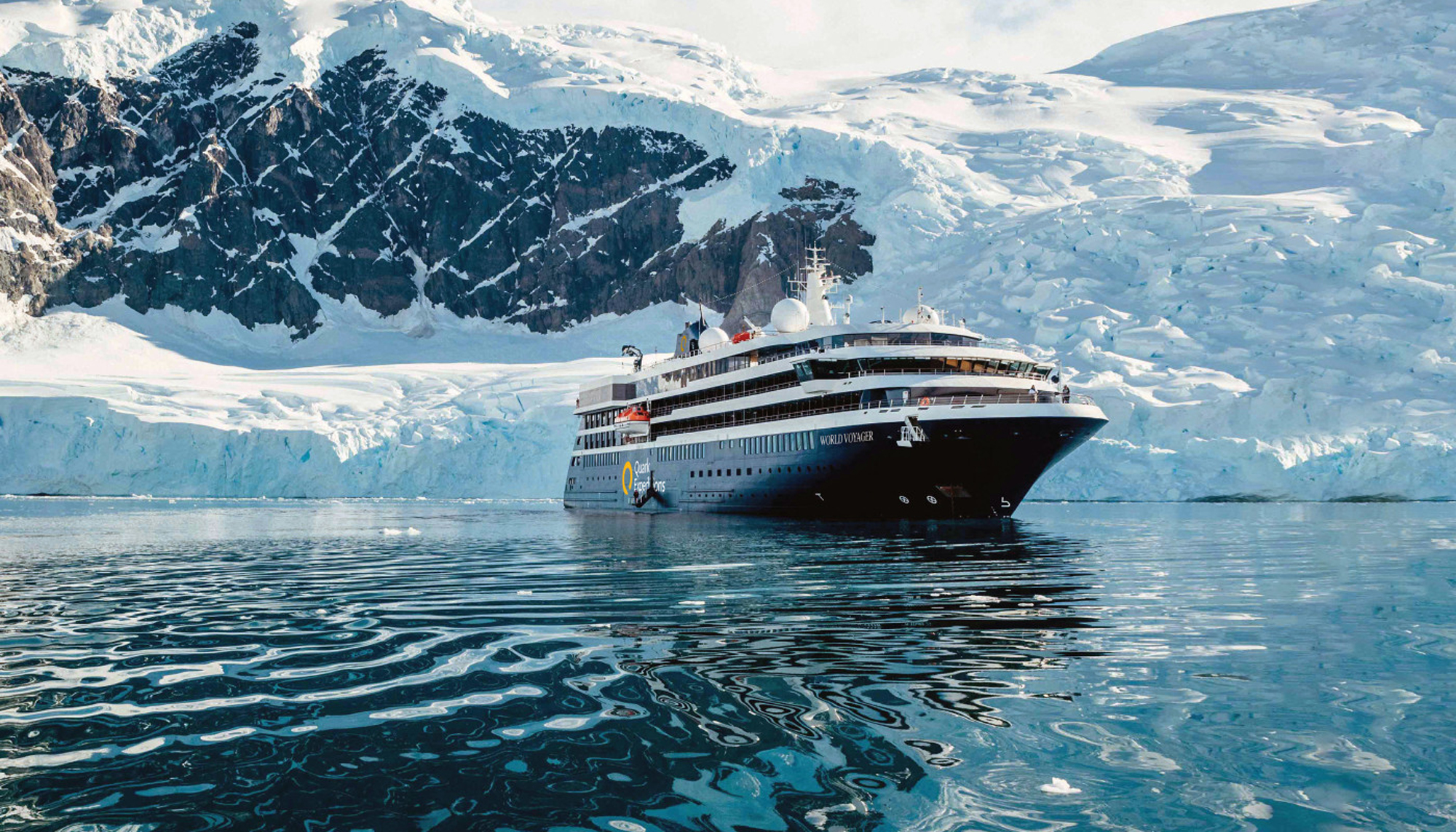 Expedition Cruise Ship in Antarctic Glacial Landscape A modern expedition cruise ship navigating through icy blue waters surrounded by snow-covered rocky