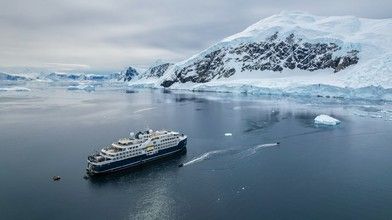 A sleek expedition cruise ship navigating through remote polar waters
