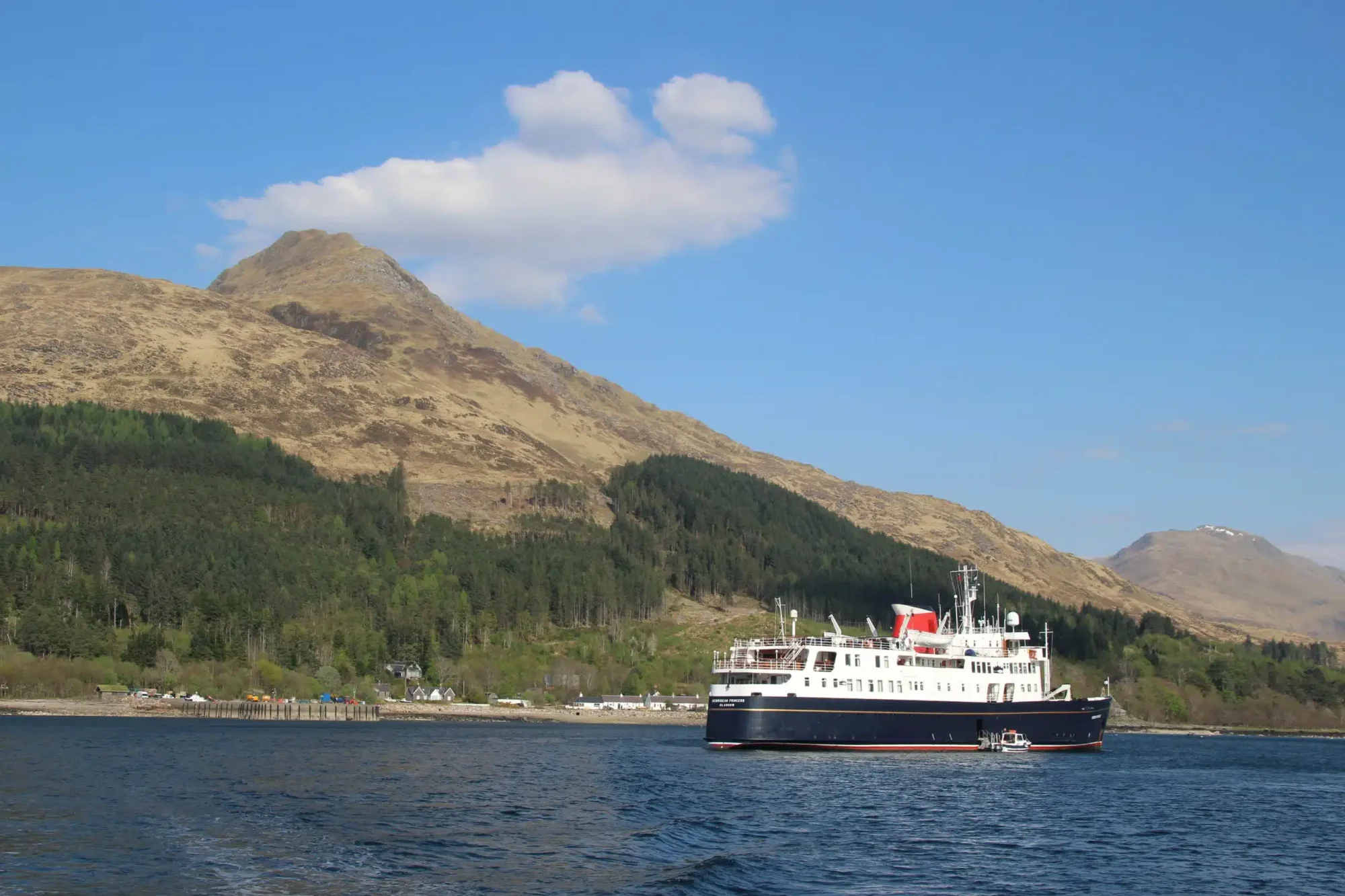 Expedition Cruise Ship in Scottish Highlands A modern expedition cruise ship anchors in a pristine Scottish loch surrounded by dramatic