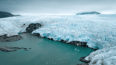 A stunning Arctic glacier descends steeply to meet turquoise glacial meltwater