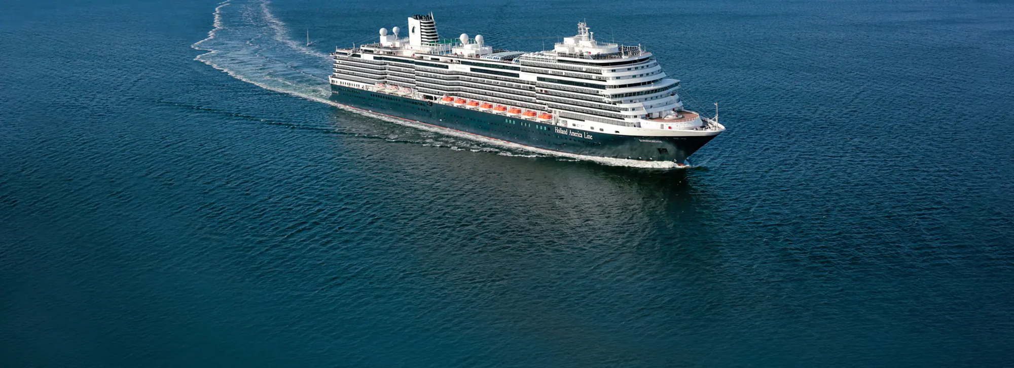 Holland America Cruise Ship at Sea A large Holland America cruise ship sailing across a deep blue ocean, creating a white wake as it