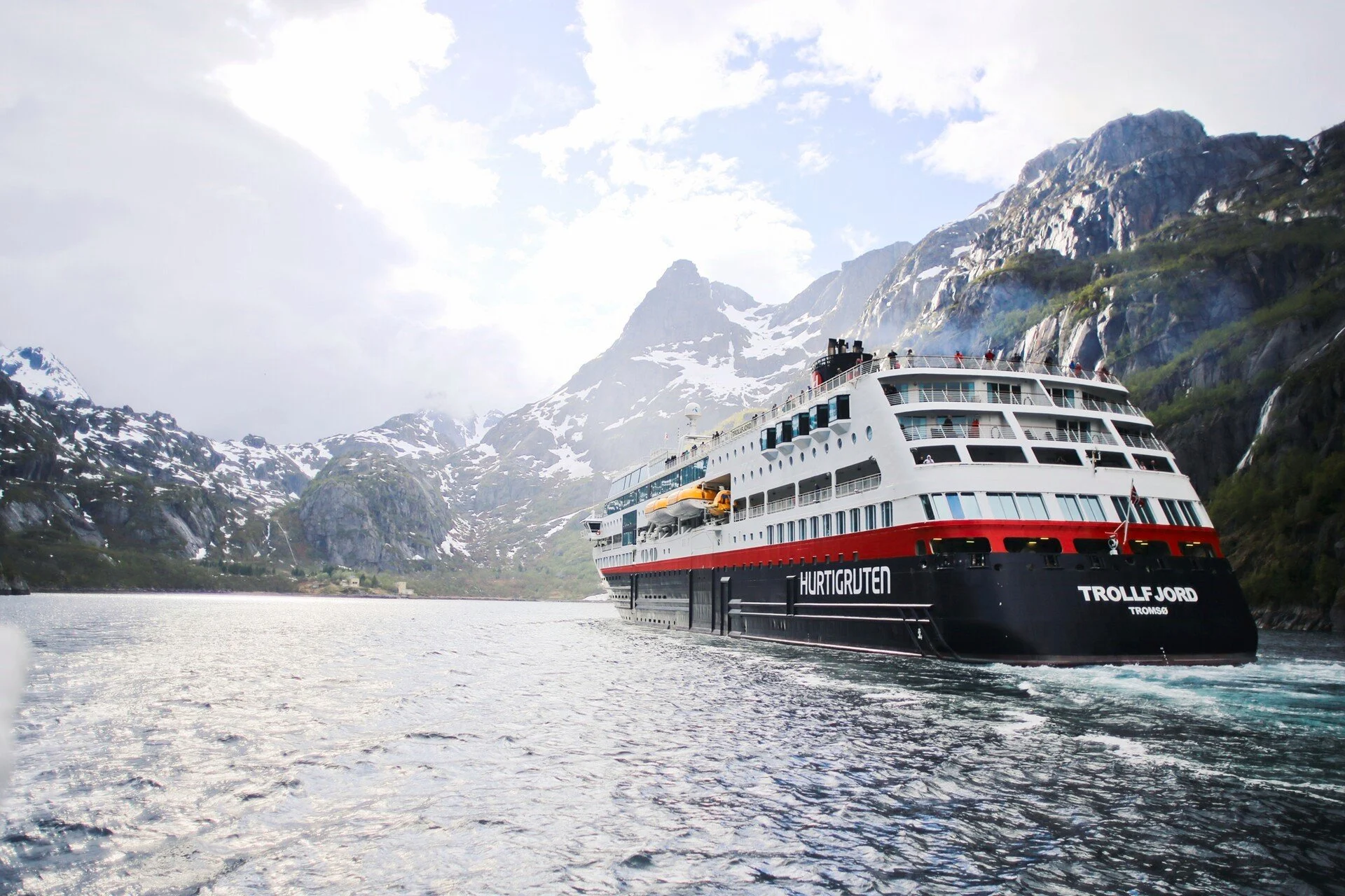 A Hurtigruten cruise ship named Trollfjord navigating through a stunning Norwegian fjord