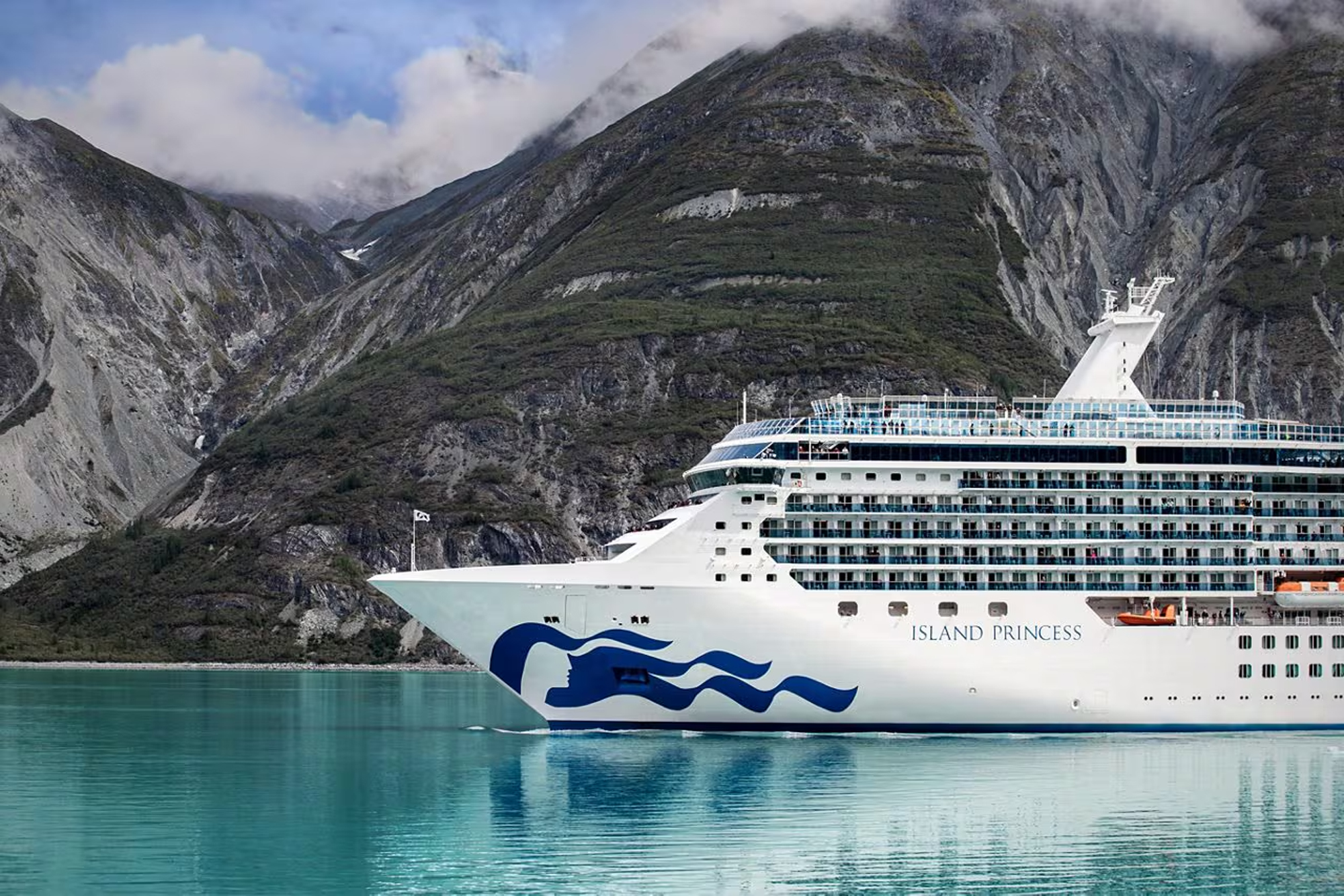 Island Princess Cruise Ship in Alaskan Fjords A white Princess Cruises ship sailing through turquoise waters with dramatic rocky mountain