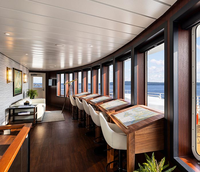 An elegant observation lounge aboard a cruise ship featuring floor-to-ceiling windows overlooking the ocean