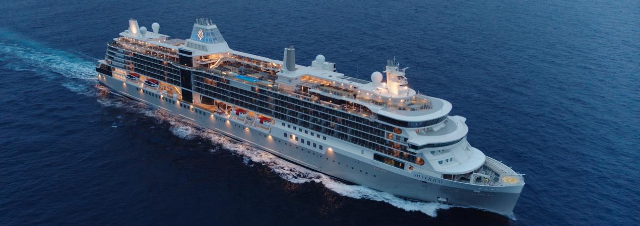 Luxury Cruise Ship Sailing on Blue Ocean A sleek, illuminated cruise ship navigating through deep blue waters, showcasing multiple decks