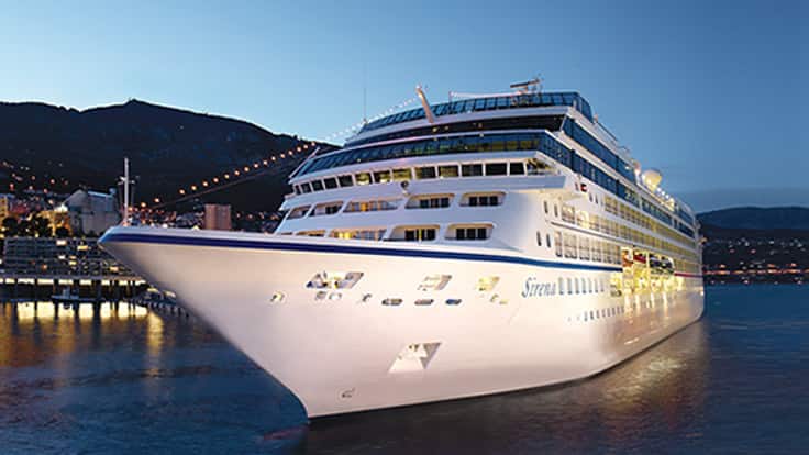 Luxury Cruise Ship at Night Oceania cruise ship docked at a scenic harbor with mountains at twilight