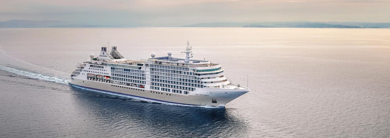 Luxury Cruise Ship at Sea A large, white multi-deck cruise ship sailing across a calm, expansive ocean with soft pastel sky