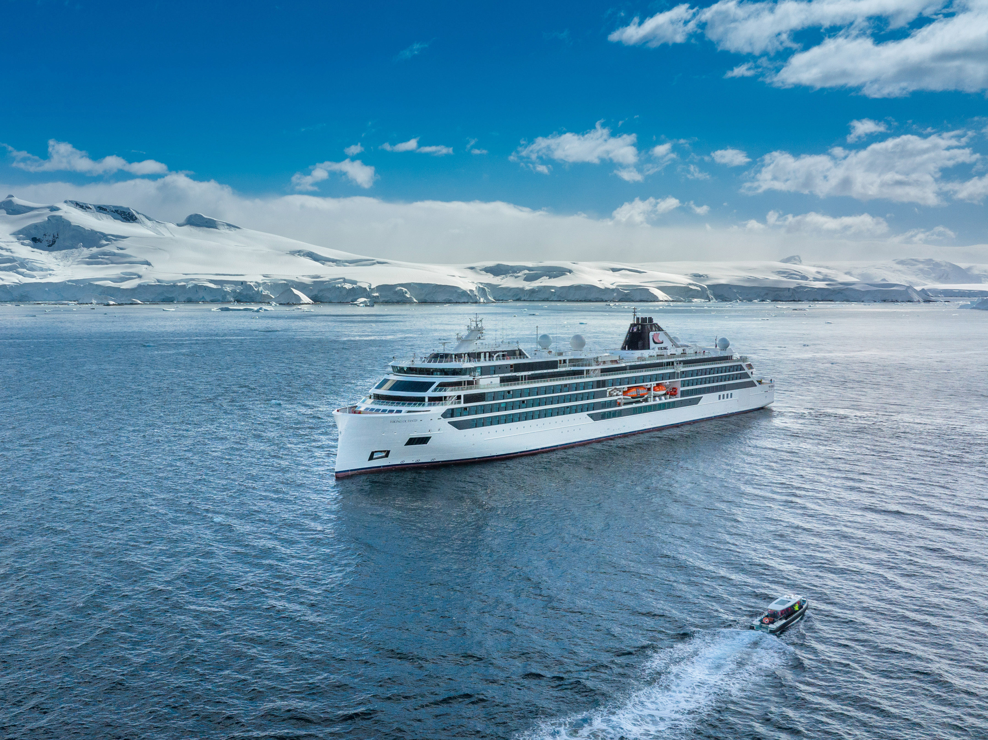 Luxury Cruise Ship in Antarctic Waters A white luxury cruise ship navigating through icy blue waters with snow-covered mountains