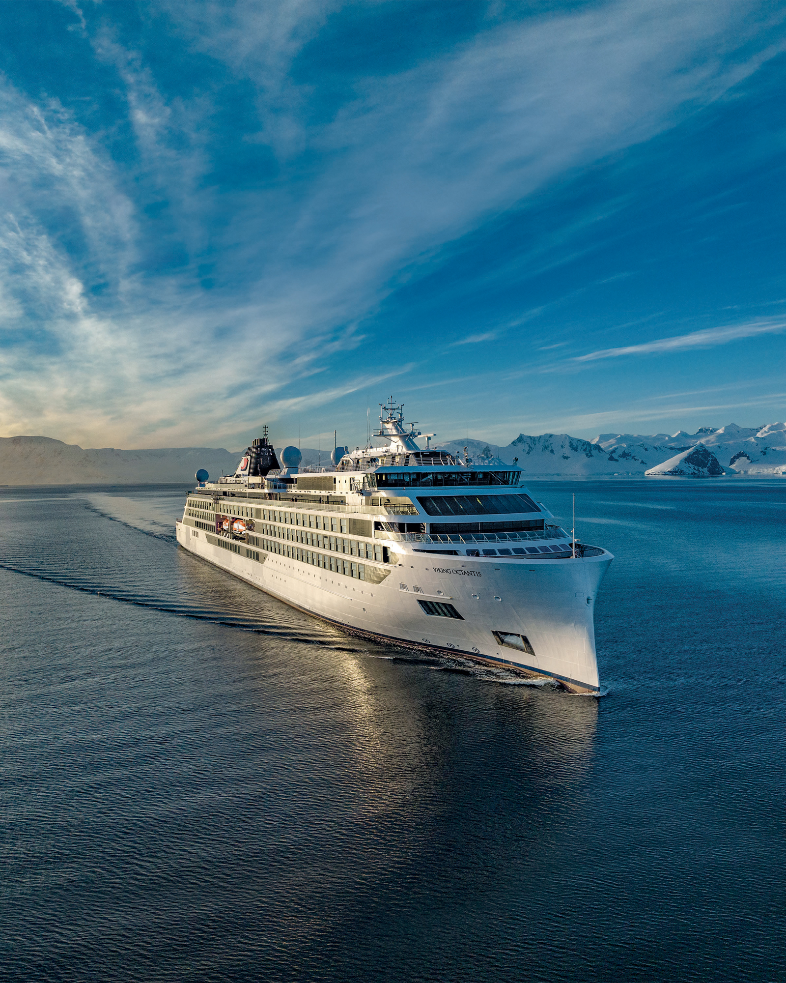 Luxury Cruise Ship in Arctic Landscape A pristine white cruise ship sailing through calm blue waters with snow-capped mountains