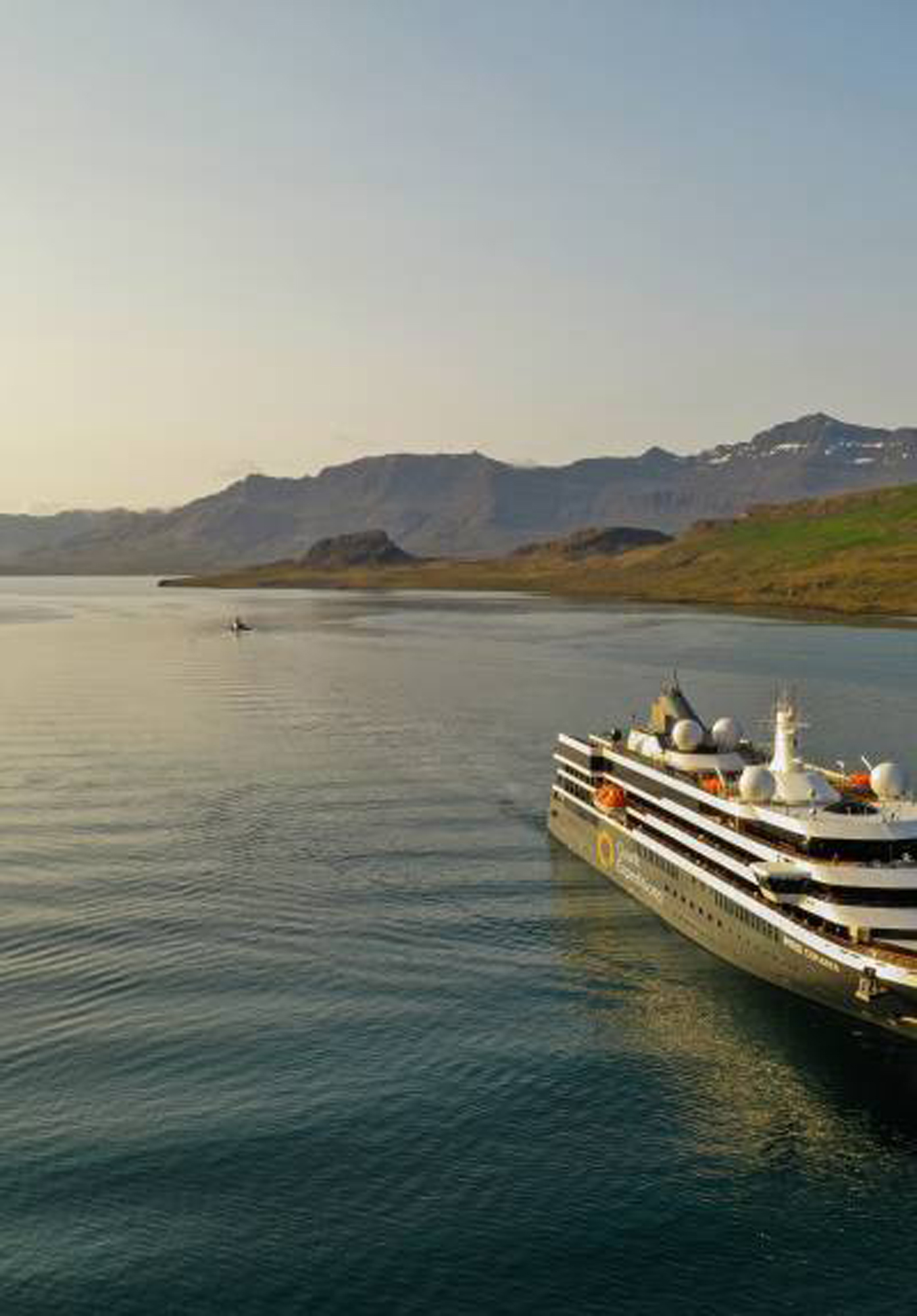 Luxury Cruise Ship in Mountainous Landscape A sleek, modern cruise ship navigates through calm waters with rugged mountain terrain in