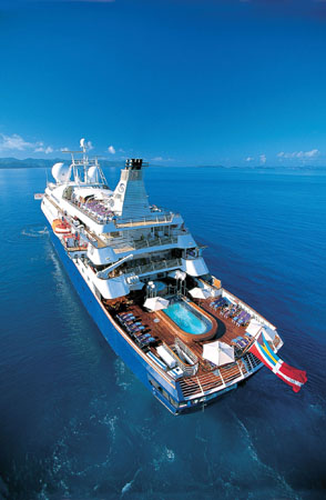 Luxury Cruise Ship on Turquoise Waters An aerial view of a pristine white cruise ship sailing on crystal blue waters, featuring multiple