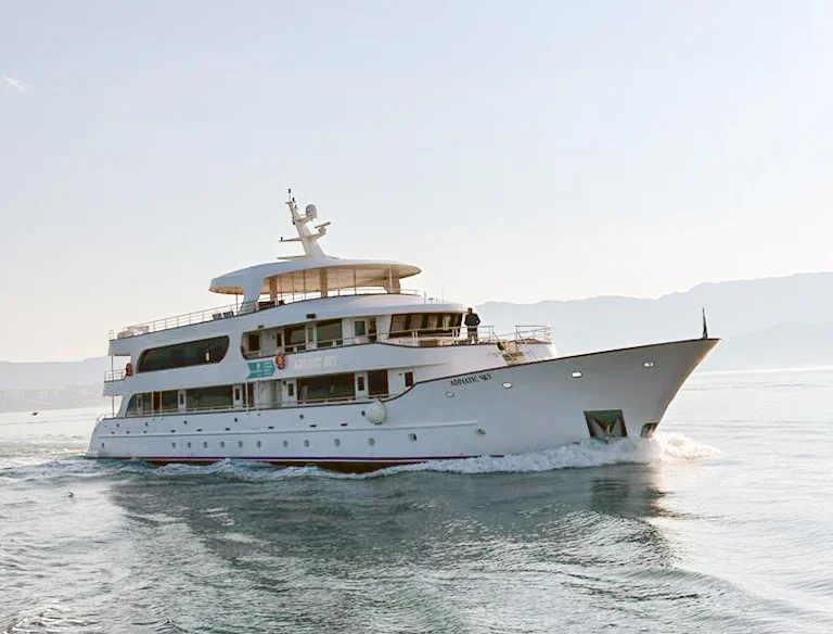 Katarina Line luxury expedition vessel anchored in shallow turquoise waters with mountainous coastline