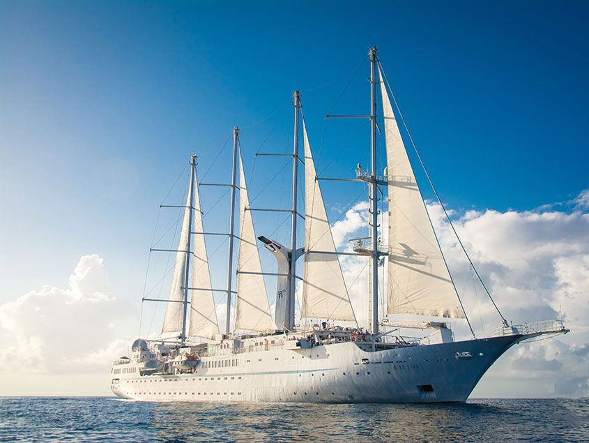 Luxury Sailing Yacht at Sea Windstar sailing yacht with white sails fully extended cruising on bright blue waters