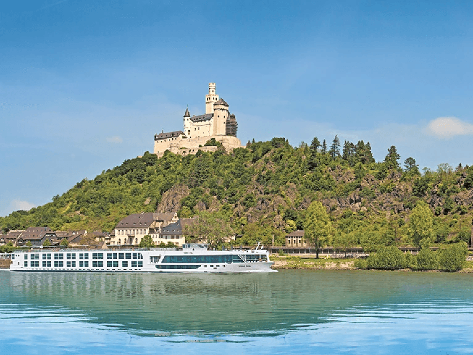 Marksburg Castle on the Rhine River A majestic medieval castle perched atop a forested hill overlooking the Rhine River, with a modern