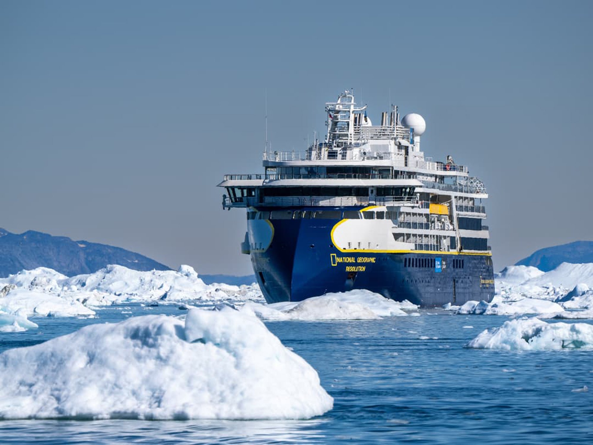 National Geographic Resolution in Antarctic Ice National Geographic Resolution navigating through icebergs and pack ice in Antarctica with snow-covered mountains