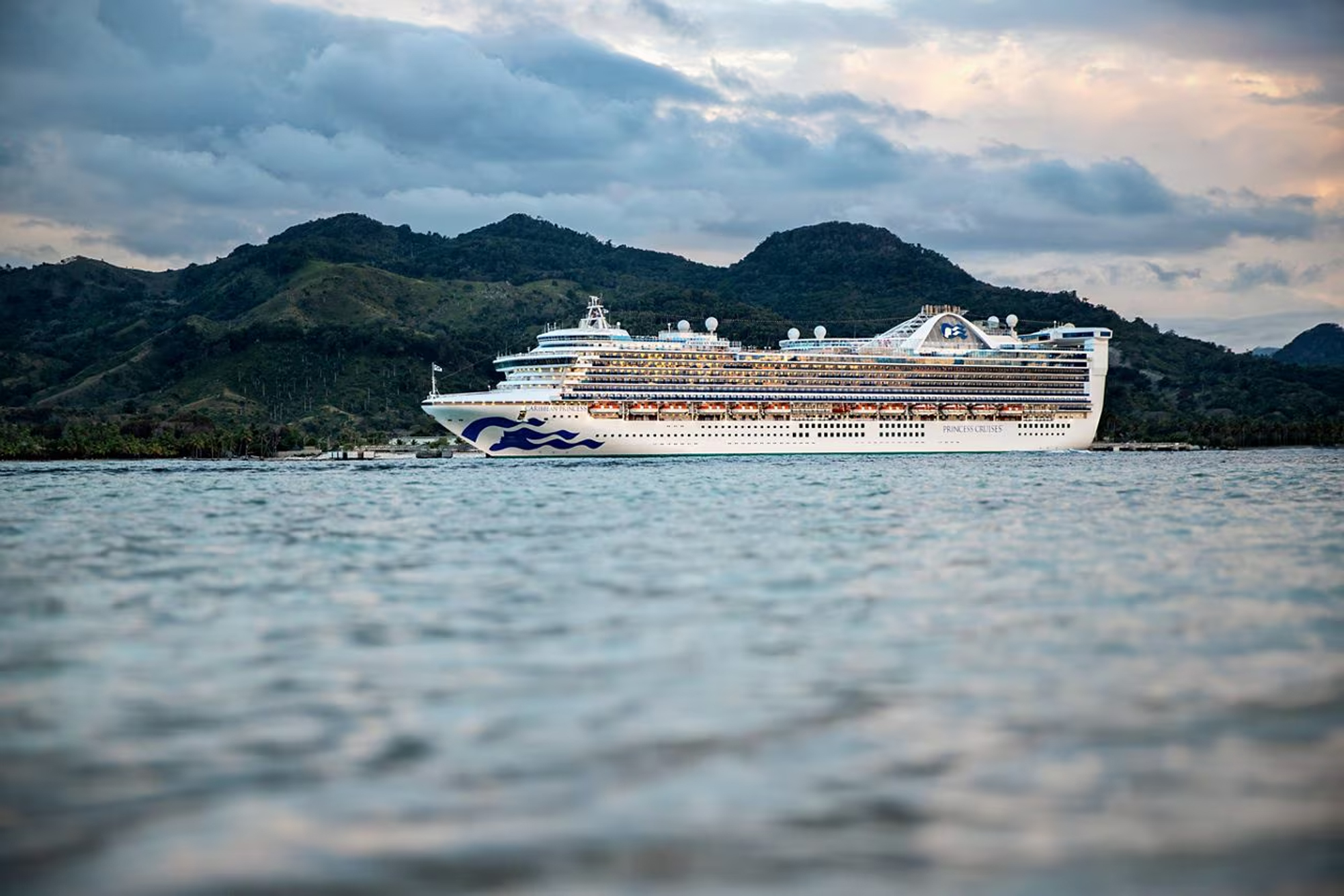 Princess Cruise Ship in Tropical Harbor A large white Princess Cruises ship anchored in a scenic bay with lush green mountains in