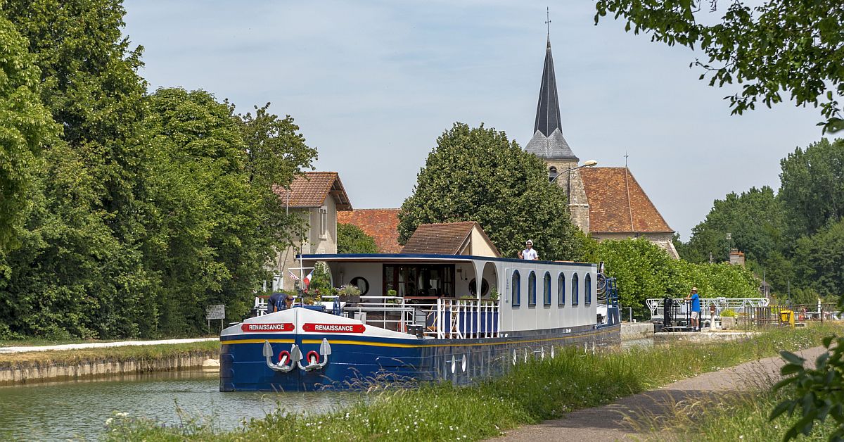 Renaissance River Cruise Boat in European Canal A Renaissance-branded river cruise boat with distinctive blue hull and white upper cabin navigates
