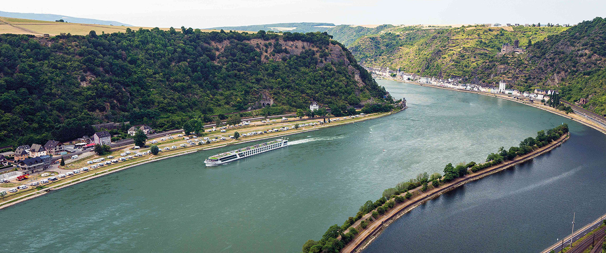 Rhine River Cruise Through Scenic Valley Rhine River cruise through scenic valley with forested cliffs and charming riverside village