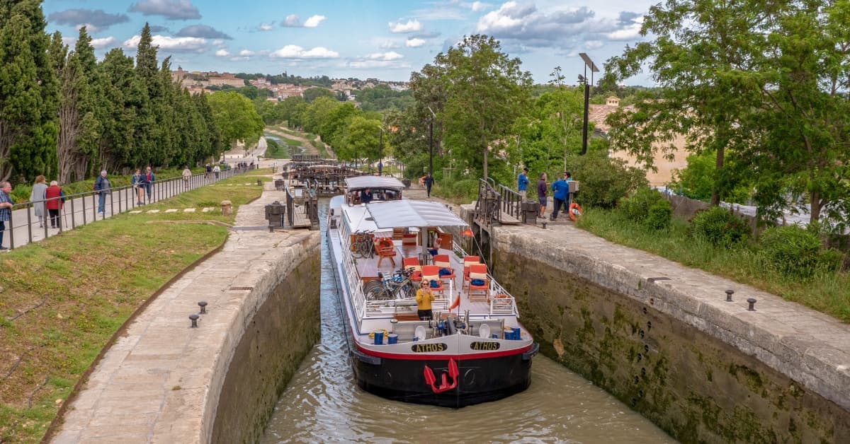 River Cruise Barge in European Canal Lock A red and white river cruise barge navigates through a stone lock system on a European waterway