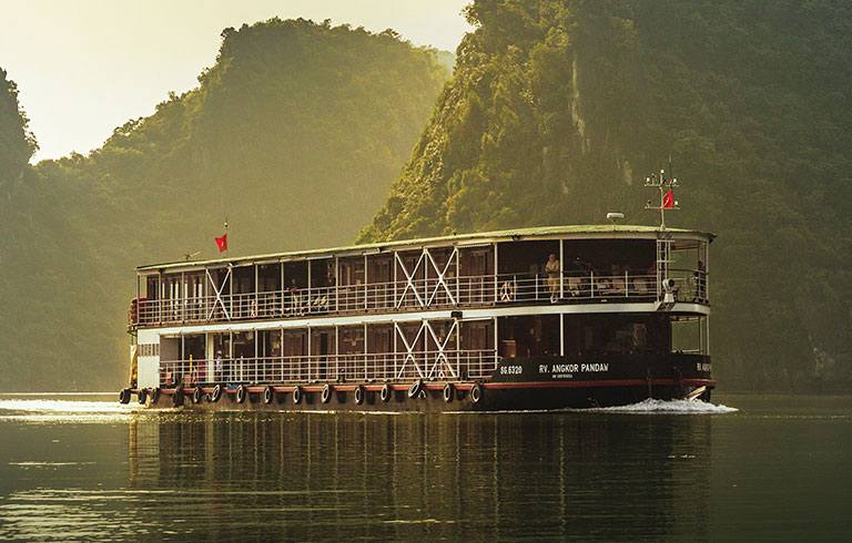River cruise boat navigating through misty mountain landscape in Asia