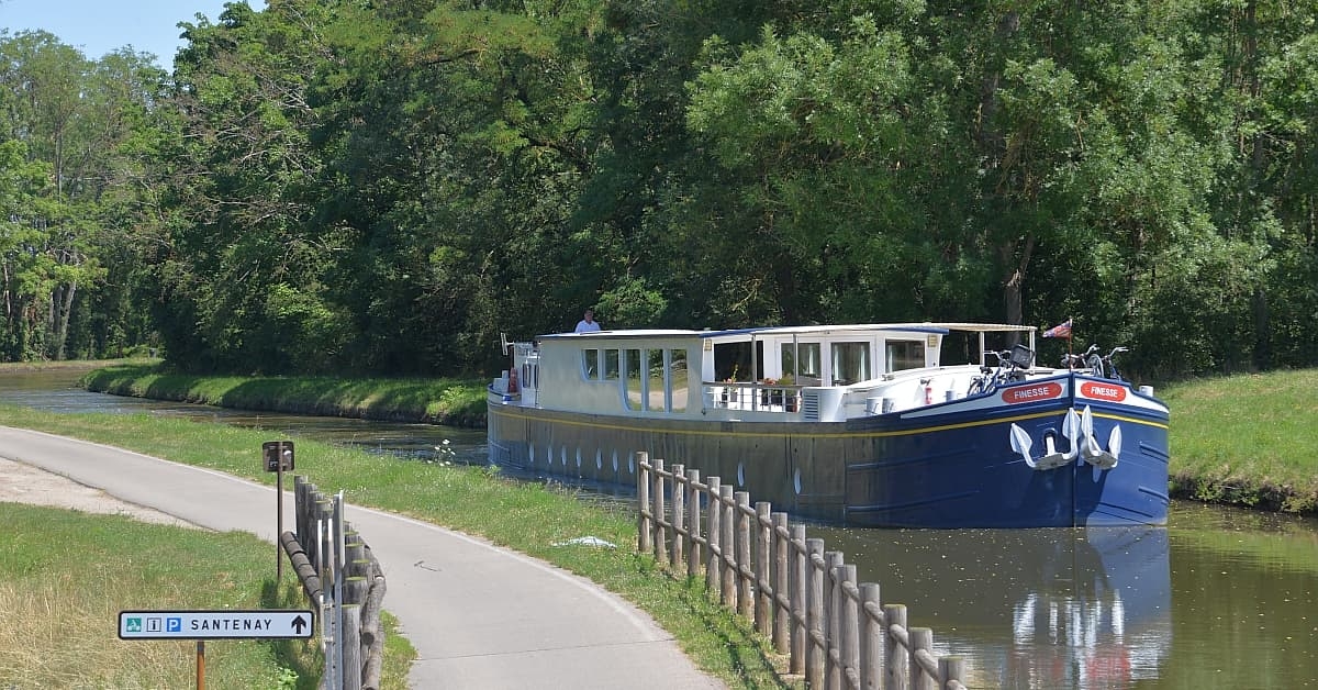 River Cruise Boat on European Waterway A modern river cruise vessel moored along a scenic European canal lined with lush green vegetation