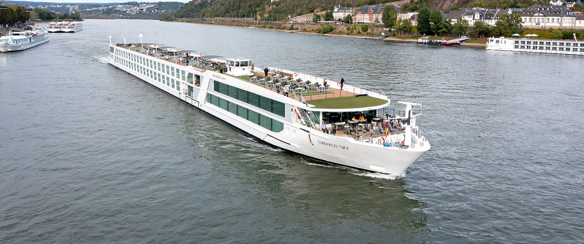River Cruise Ship on European Waterway A modern white river cruise ship sailing along a scenic river with historic buildings and landscape