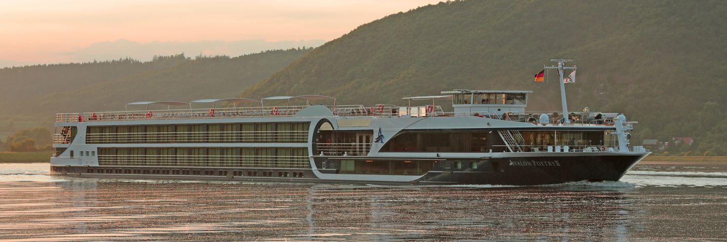 River Cruise Ship on Scenic European Waterway A modern river cruise vessel sailing on a calm river with forested hills in the background during