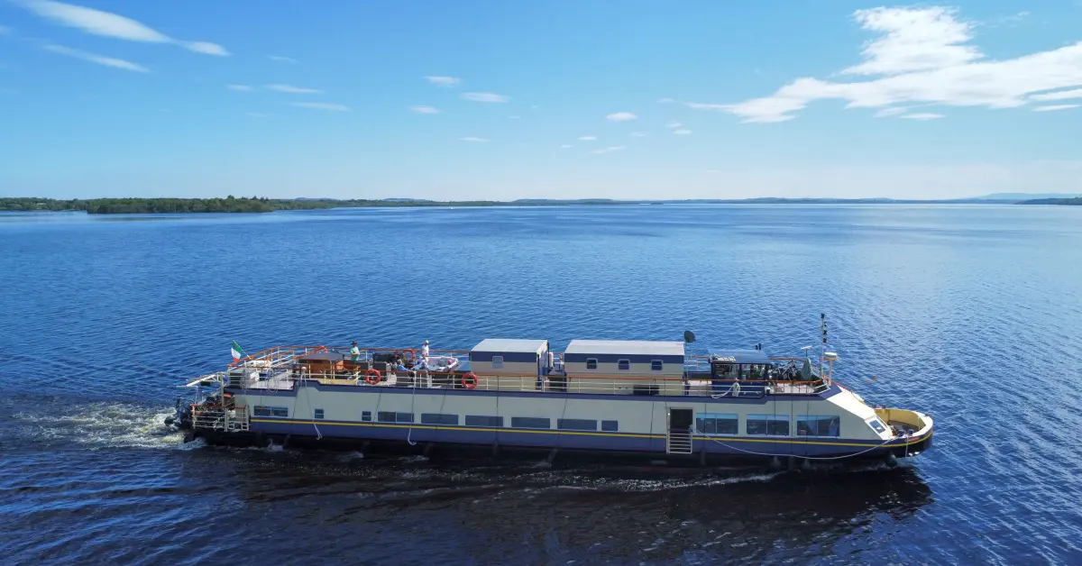 Riverboat Cruise Ship on Scenic Lake A multi-deck riverboat or lake cruise vessel anchored in calm blue waters with forested shoreline