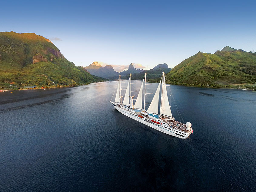 Sailboat Cruising Tropical Mountain Coastline Windstar sailing vessel navigating through scenic waterway with lush green mountains