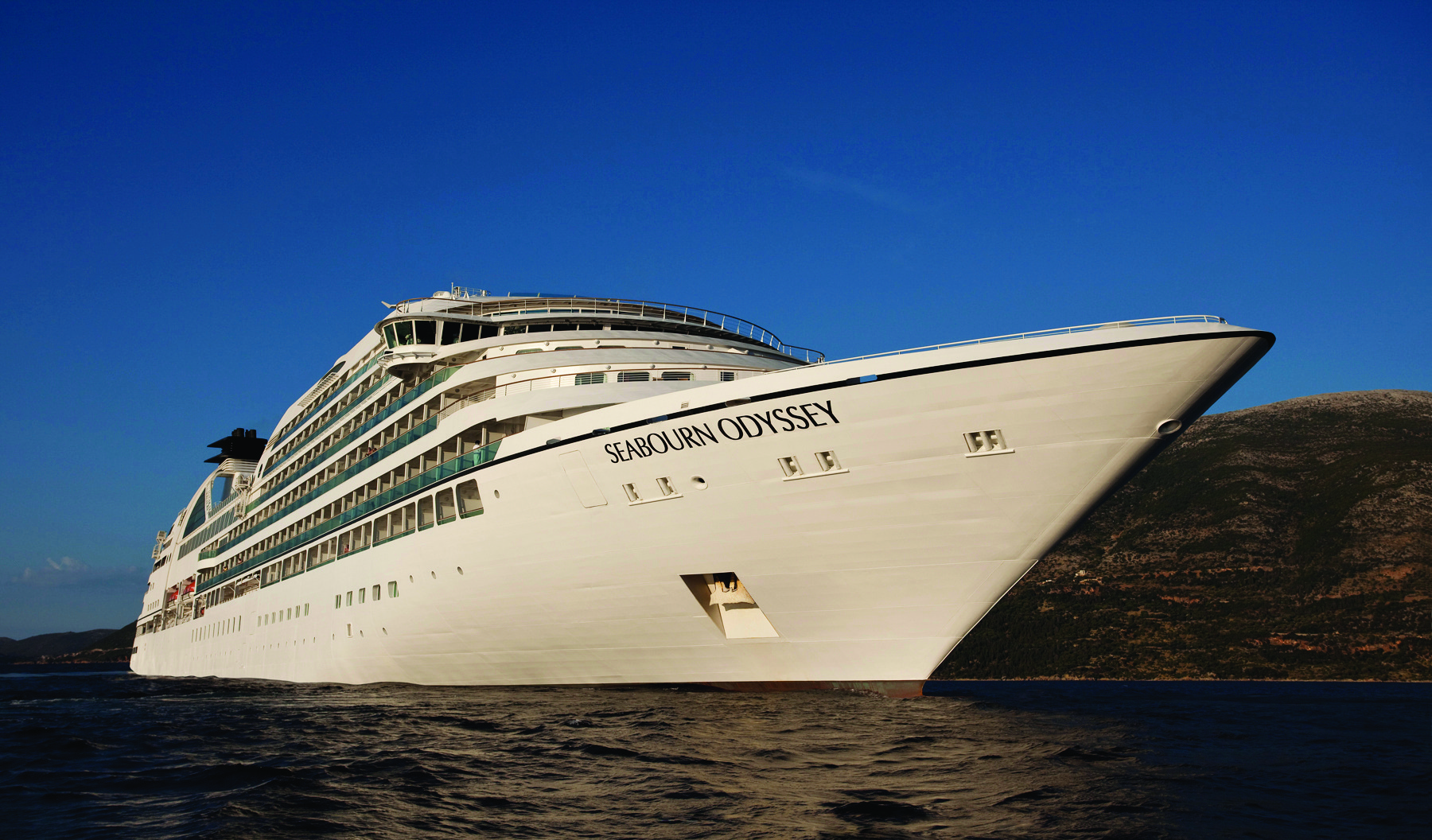Seabourn Odyssey at Sea- Bow Seabourn Odyssey luxury cruise ship anchored in clear blue waters near rocky coastline