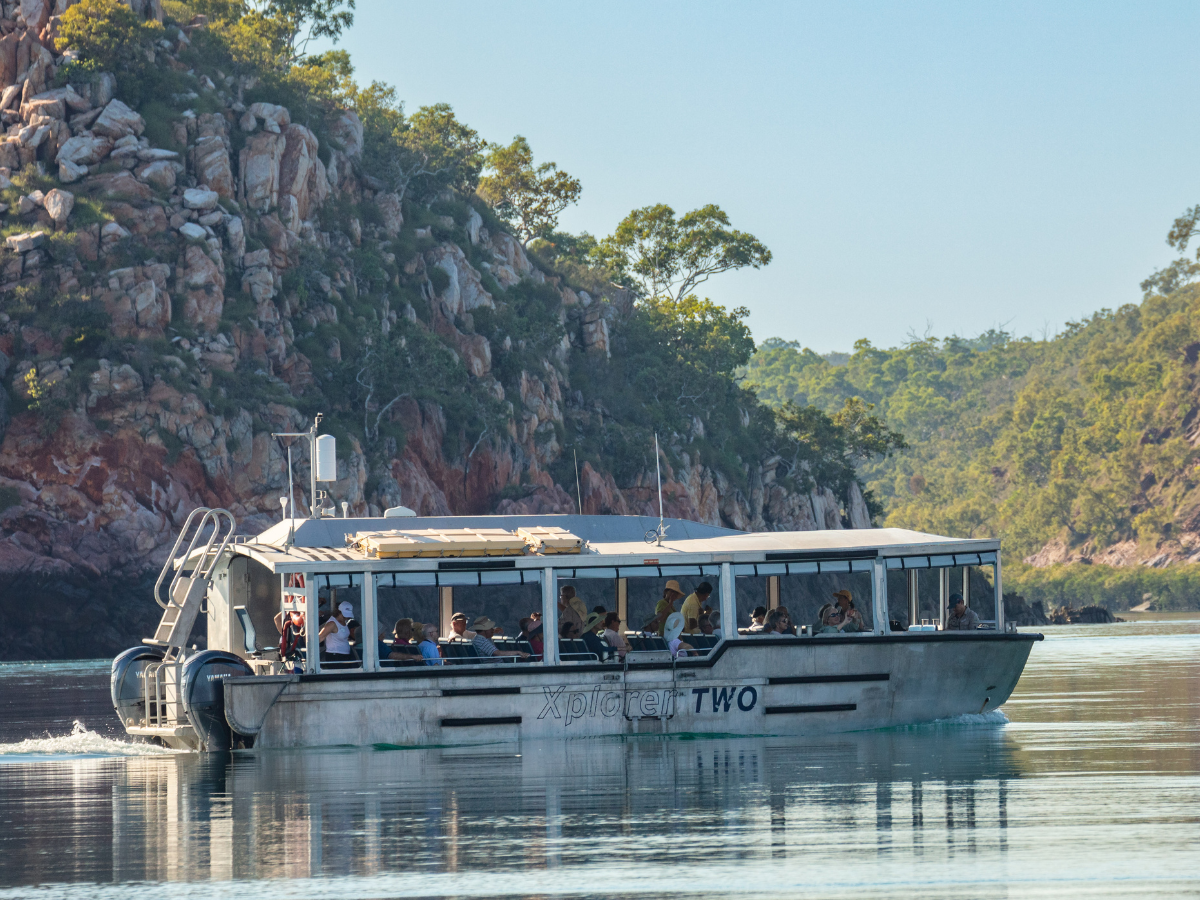 Tourist Boat Cruising Rocky Coastline Xplorer tender vessel cruising through rocky Kimberley coastline with passengers aboard