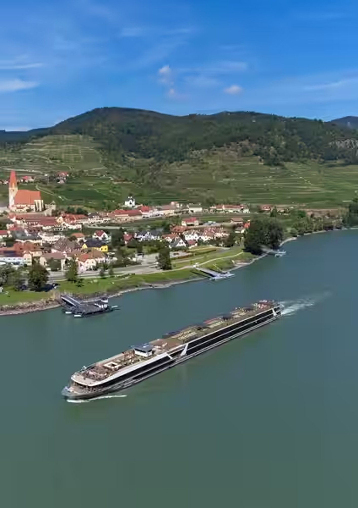 t-eu-vega-river-ship-exterior-03-2022 Travelmarvel river cruise ship sailing through a European river valley with vineyards